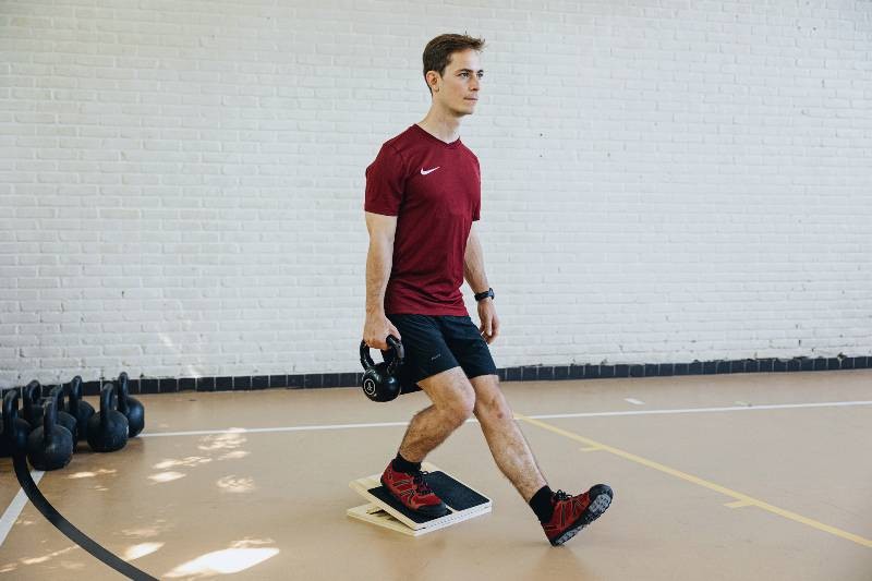 an athlete doing a reverse step-up on the slant board