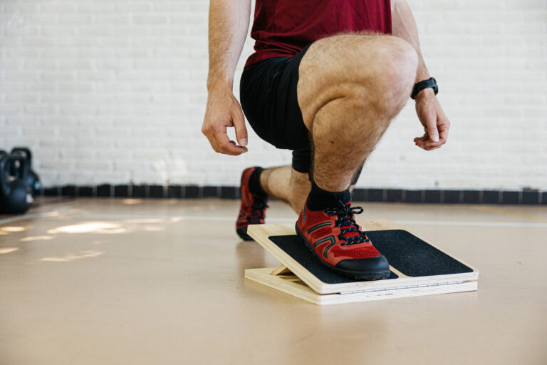 An athlete doing a split squat on a slant board with their knees going over their toes