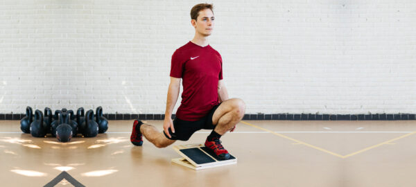 Athlete doing a knees-over-toes split squat on a slant board