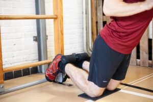 an athlete using the nordic hamstring curl strap